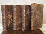trois vieux livres posés sur une chaise en bois près d'un mur
