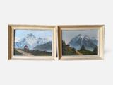 two framed paintings of mountains and houses on a white wall