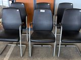 quatre fauteuils en cuir noir aux pieds chromés dans une pièce