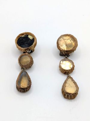 two pairs of gold and black stone earrings on a white surface