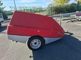 a red and white boat on a trailer in a parking lot