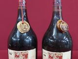 two bottles of wine sitting next to each other on a red surface