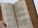 someone is holding an open book in their hand on a white surface