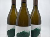 trois bouteilles de vin recouvertes de peinture verte, posées sur une surface blanche