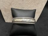 a pair of silver bracelets sitting on top of a black pillow