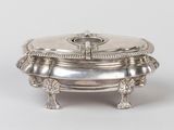 a silver plate with a lid on a stand on a white surface