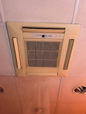 Un climatiseur de marque Fujitsu, encastré en plafond, avec …