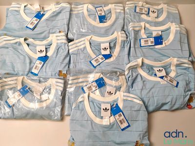 une pile de vêtements de bébé bleus et blancs posée sur une table