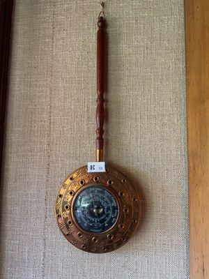 une horloge accrochée au mur, munie d'une poignée en bois
