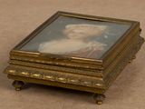 a small gold box with a picture of a woman on it