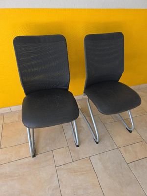 deux chaises noires placées l'une à côté de l'autre sur un sol carrelé