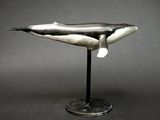 sculpture d'une baleine à bosse posée sur un socle, sur fond gris
