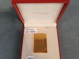 un briquet plaqué or dans une boîte rouge posée sur une table