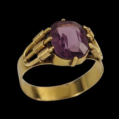 gros plan d'une bague en or avec une pierre violette
