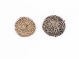 two silver and gold coins sitting next to each other on a white surface