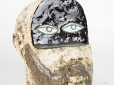 a ceramic sculpture of a man ' s face with green eyes