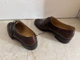 pair of brown shoes sitting on a marble floor next to a white wall