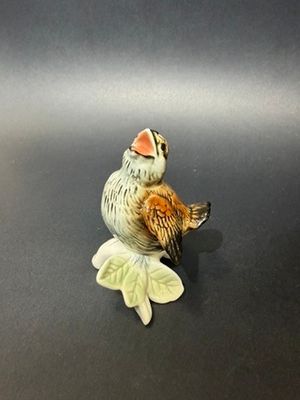 a figurine of a bird sitting on a leaf