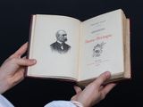 une personne tenant un livre ouvert sur lequel figure le dessin d'un homme