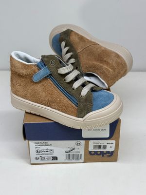 une paire de baskets marron et bleues posée sur une boîte en carton