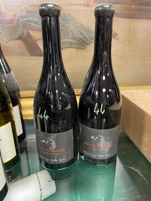 three bottles of wine sit on a glass table next to a bottle of wine
