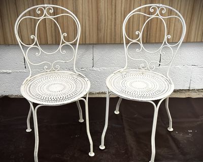une paire de chaises de jardin blanches en fer forgé posées sur un tapis noir
