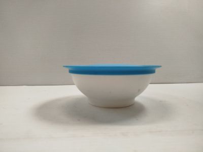a white bowl with a blue lid sitting on a table