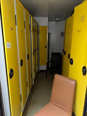 yellow lockers line a hallway with a chair in the middle of it