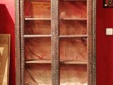 une armoire en bois avec des portes vitrées dans une pièce rouge