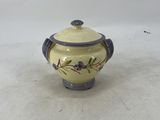 a small yellow and purple vase with a lid