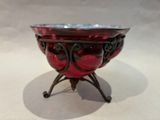 a red glass bowl on a stand on a white surface