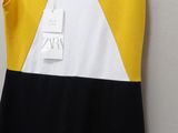 yellow and black dress hanging on a hanger on a white wall