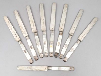 six couteaux argentés sont disposés en cercle sur une surface grise