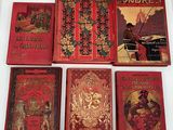 six livres rouges empilés les uns sur les autres sur une surface blanche