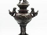a bronze urn with a statue on top of it