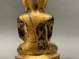 statue of a person sitting in a meditation position on a black and gold base