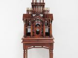 a small wooden birdcage on a stand in front of a painting