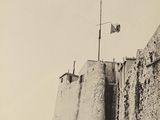une photo en noir et blanc d'un homme debout devant un mur de pierre