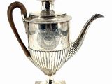 an antique silver teapot with a wooden handle on a stand