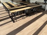 une longue table et des chaises dans une pièce au sol en parquet
