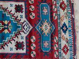 a red and blue rug sitting on top of a tiled floor