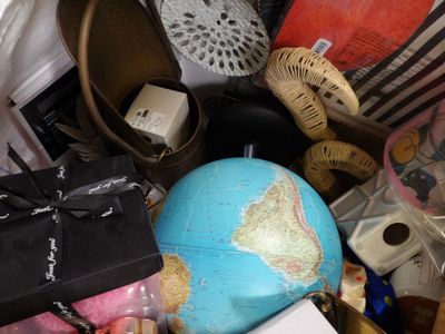 a pile of stuff that includes shoes, a globe, a purse, and other items