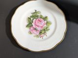 an old china plate with a pink rose on it on a black table