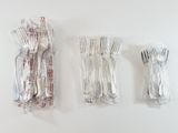 three forks and spoons wrapped in foil on the wall