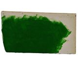 green paint on a piece of paper on a white surface
