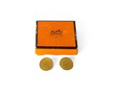 une boîte orange contenant deux pièces d'or posées l'une à côté de l'autre
