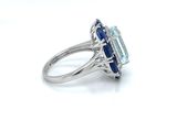 a close up of a diamond and sapphire ring on a white surface
