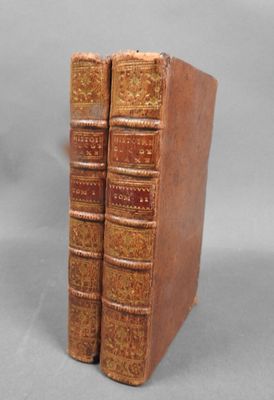 two old books sitting on top of each other on a table
