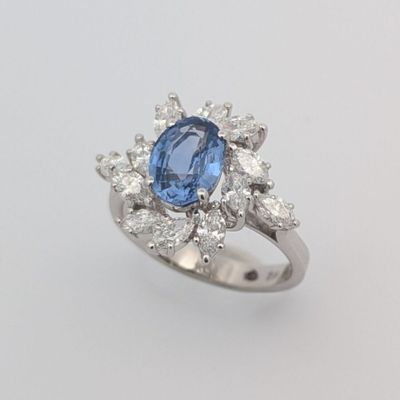 gros plan d'une bague avec une pierre bleue entourée de diamants blancs