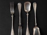 four forks and spoons on a black surface with a black background